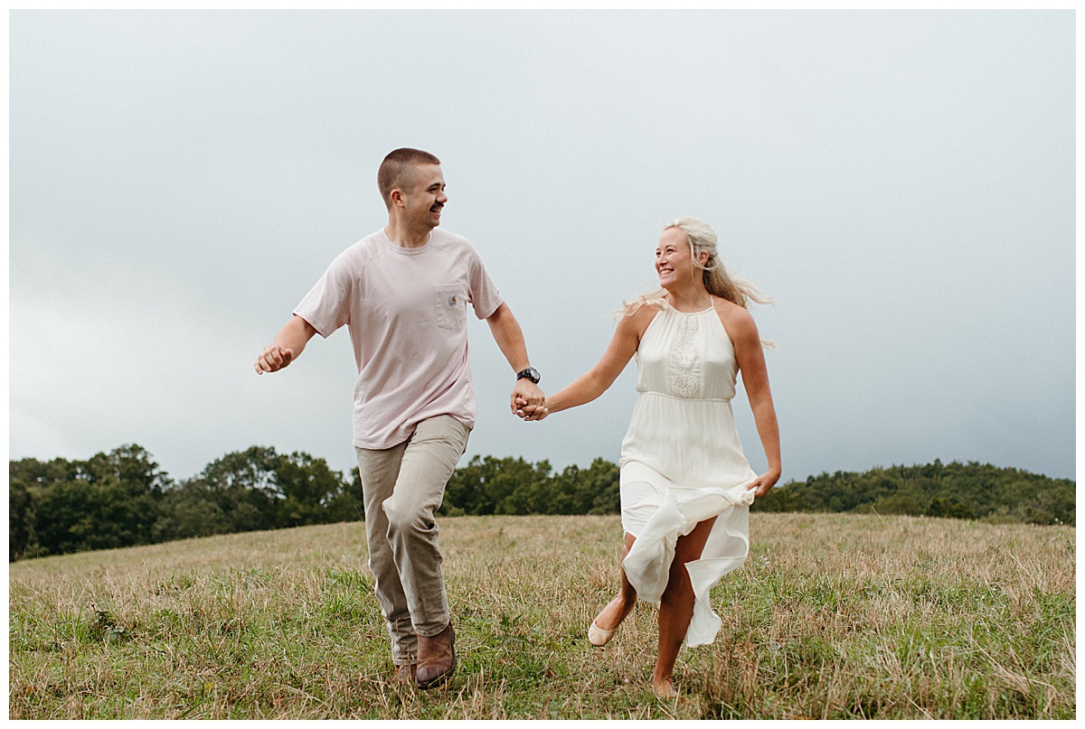 engaged couple running through the field boone nc